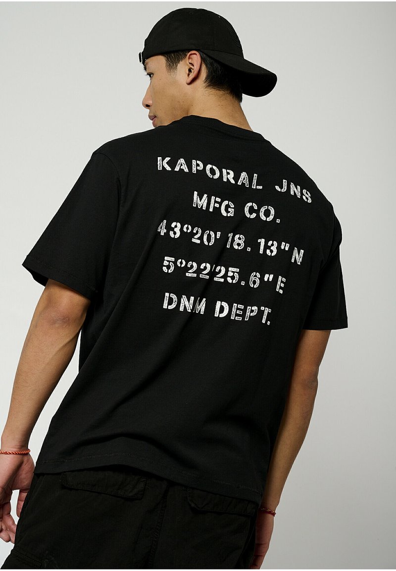 T-shirt en coton noir à manches courtes, avec un grand texte imprimé en blanc au dos, incluant des coordonnées et des détails de la marque.