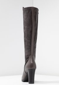 Bottes marron à hauteur de genoux avec une texture semblable à du daim, des accents en cuir, un talon empilé, un détail de couture verticale et une fermeture éclair.