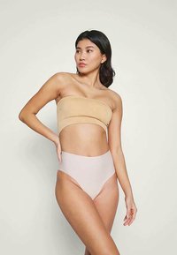 Béžový bandeau top bez ramínek spárovaný se světle růžovými vysokými kalhotkami. Hladká, elastická tkanina s bezešvým designem.