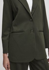 Olivově zelený blazer z pružné tkaniny, v úzkém střihu, s klopami, dvojitým knoflíkovým zapínáním, postranními kapsami a hladkým povrchem.