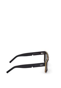 Černé sluneční brýle s tlustým černým rámečkem, žlutými a červenými akcenty na okrajích a texturovaným povrchem na ramenech.