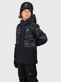 Kind, das eine schwarze und graue camouflierte Winterjacke, schwarze Schneehosen, schwarze Handschuhe, eine Strickmütze und eine Skibrille auf dem Kopf trägt, schaut zur Seite.