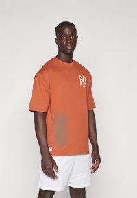 Oranje katoenen T-shirt met ronde hals, voorzien van een witte NY-logo op de linkerborst en een klein logopatch op de onderzoom.
