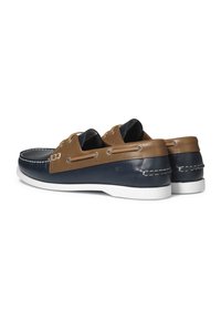 Námořnické a hnědé kožené lodní boty s bílými podrážkami, zdobené švy a kovovými oky na tkaničky. Zaoblený tvar, casual design.