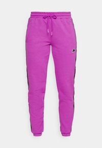 Pink sweatpants with an elastic waistband and drawstring, featuring side pockets and contrasting black side stripes with a logo accent.