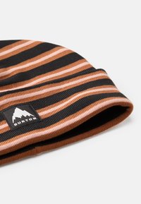 Căciulă dungi în negru, maro și roz. Textură tricotată, design pliabil, cu o etichetă neagră ce prezintă un logo de munte și numele mărcii.