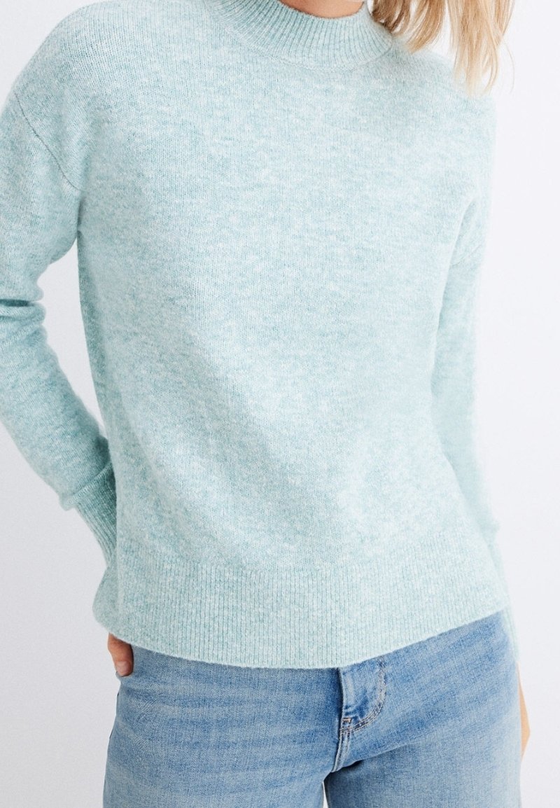 Light blue knit sweater with a ribbed crew neckline and cuffs, featuring a soft texture and a slightly loose fit. Paired with denim jeans.