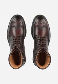 Bottines en cuir marron avec détails brogue, bout rond et design à lacets. Dotées d'un intérieur beige contrastant et d'une fermeture éclair latérale.