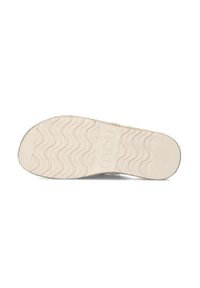 Off-white rubberen zool met golvenpatroon, voorzien van een textuur. Logo zichtbaar in het midden. Platte, ronde vorm.