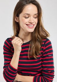 Rood en marineblauwe gestreepte lange mouwen shirt met een ronde halslijn, voorzien van een klein logo op de mouw en een zachte katoenen textuur.