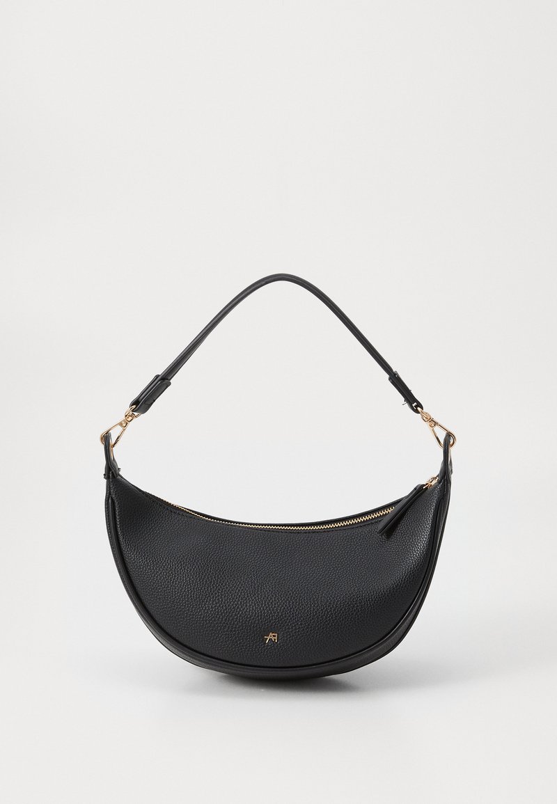Bolsa de ombro em couro preto com forma curva, superfície texturizada, fecho dourado e uma alça curta. Apresenta um detalhe de logótipo minimalista.