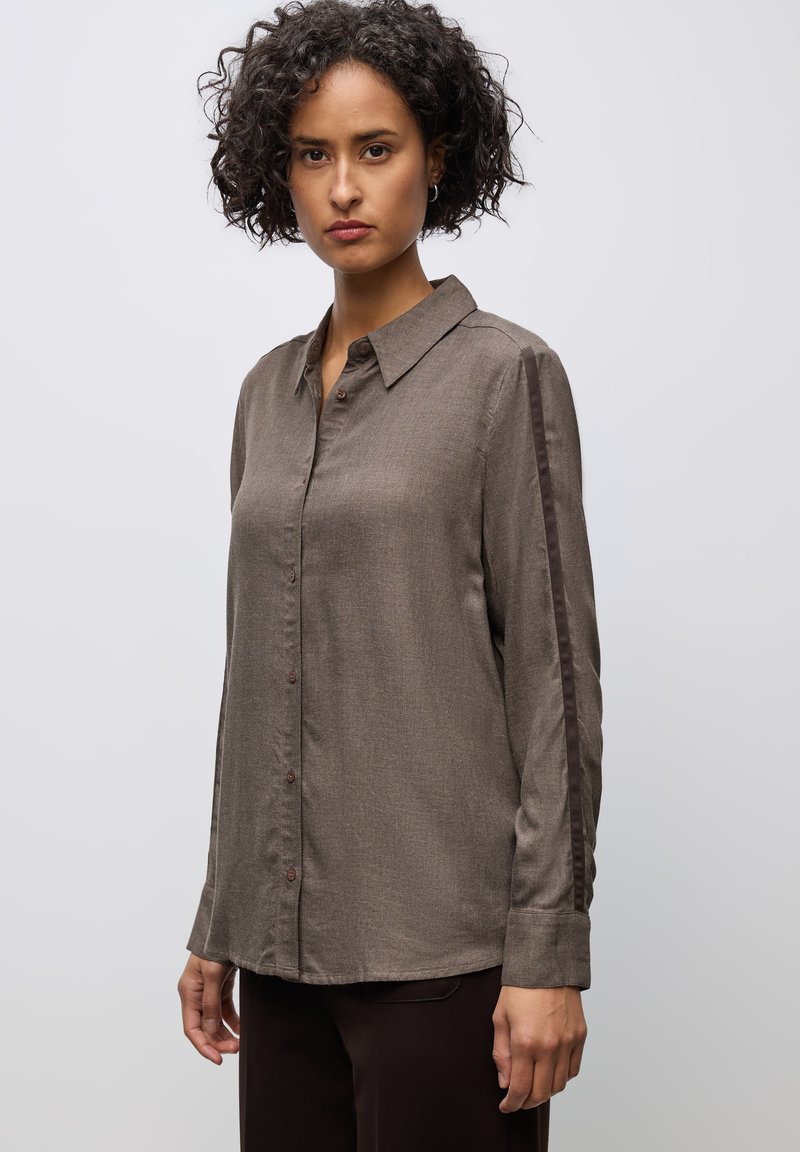 Chemise boutonnée marron à manches longues avec une finition texturée, panneaux latéraux dans une teinte plus sombre et un col classique.