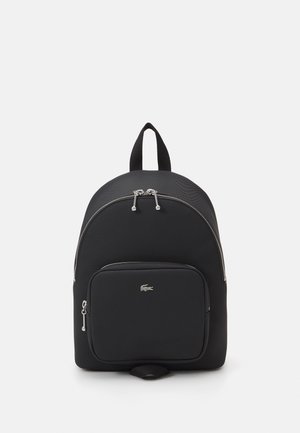 Sac à dos en nylon noir, de forme arrondie, avec des fermetures éclair argentées, une poche zippée à l'avant et un petit logo. Dispose d'une poignée supérieure et de bretelles rembourrées.