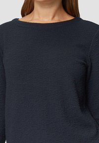 Top de manga larga texturizado en color marino con cuello redondo, que presenta un patrón sutil y un corte relajado para mayor comodidad. Acabado de tejido suave.