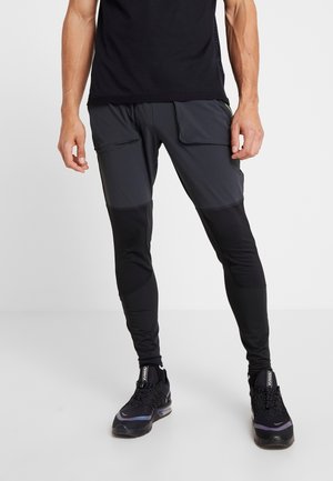 Svarta träningsbyxor med kontrasterande grå paneler, med sidofickor och en figurnära design. Ytan är slät med mesh-detaljer vid underbenen.