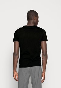Black short-sleeve t-shirt made of soft fabric, featuring a round neck and a fitted silhouette. Visible stitching details at the shoulders.