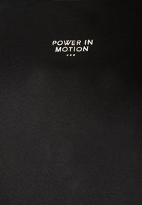 Μαύρο ύφασμα με λευκή κεντημένη επιγραφή «POWER IN MOTION» στο κέντρο κοντά στην κορυφή, ακολουθούμενη από τρεις μικρές τελείες κάτω από το κείμενο.