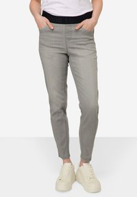Pantalones de mezclilla grises con una cinturilla elástica negra, ajuste slim, bolsillos delanteros y una textura suave, combinados con zapatillas de plataforma blancas.