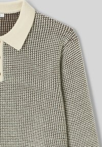 Polo shirt avec un motif texturé marron et crème, col beige et trois boutons le long de la patte de boutonnage.