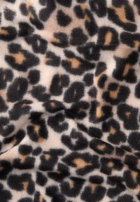 Leopardų rašto pūkuota medžiaga su šviesiai ruda fono spalva ir juodais bei rudo spalvos dėmėmis, minkšta tekstūra ir šiek tiek raukšlėta išvaizda.