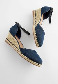 Tumed denim vöödiga kingad ümarate varvastega, espadrille-stiilis jute sisetallaga ja musta pahkluustrassiga. Omab õmmeldud detaile tallal.