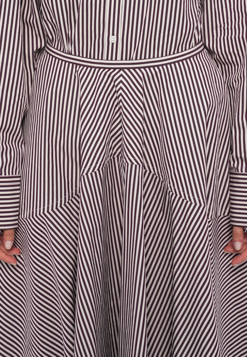 Randig klänning med mörklila och vita diagonala ränder, med ett lagerdesign, midjebälte och knäppning fram.