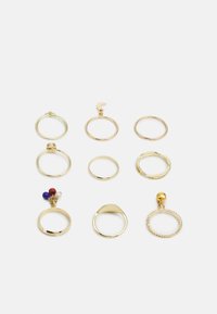 Conjunto de nove anéis em metal dourado. Inclui bandas simples, um design texturizado e um com acentos de contas coloridas. Várias formas e tamanhos.