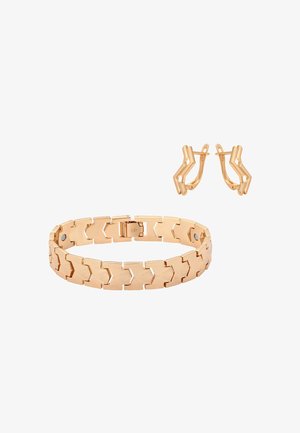 Armband in Gold-Ton mit ineinandergreifenden Chevron-Gliedern und passenden Chevron-förmigen Clip-on-Ohrringen auf weißem Hintergrund.