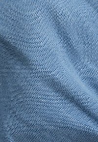 Tissu tricoté bleu clair présentant un tissage texturé avec une apparence douce et un motif cohérent à travers l'ensemble.