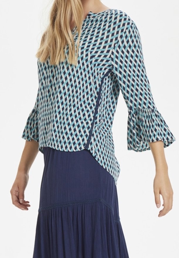 Top blu e bianco con maniche a campana, caratterizzato da un design geometrico. Il tessuto appare leggero con una vestibilità comoda.