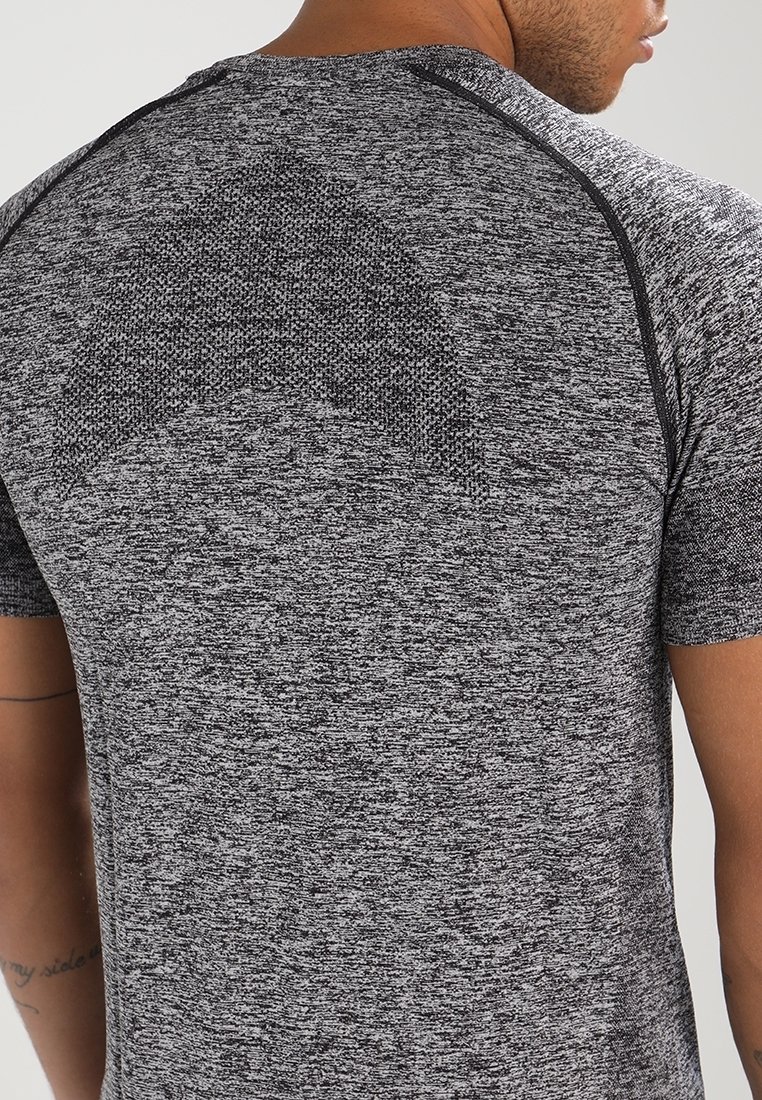 Grå atletisk t-shirt med en texturerad stickad mönster, korta ärmar och kontrasterande svart sömnad längs axlarna och ryggen.