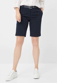 Navyblauwe katoenen shorts met een gladde textuur, riemlussen en een rechte snit, gecombineerd met witte sneakers met een lage profiel en veters.