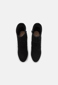 Černé semišové kotníkové boty s hladkým povrchem, bočním zipem a elegantním tvarem. Zaoblená špička a minimalistický design.