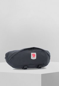 Crni načičak od tkanine s okruglim oblikom, s gornjim zatvaračem, prednjom oznakom logotipa i dvjema bočnim petljama za pričvršćivanje ili nošenje.
