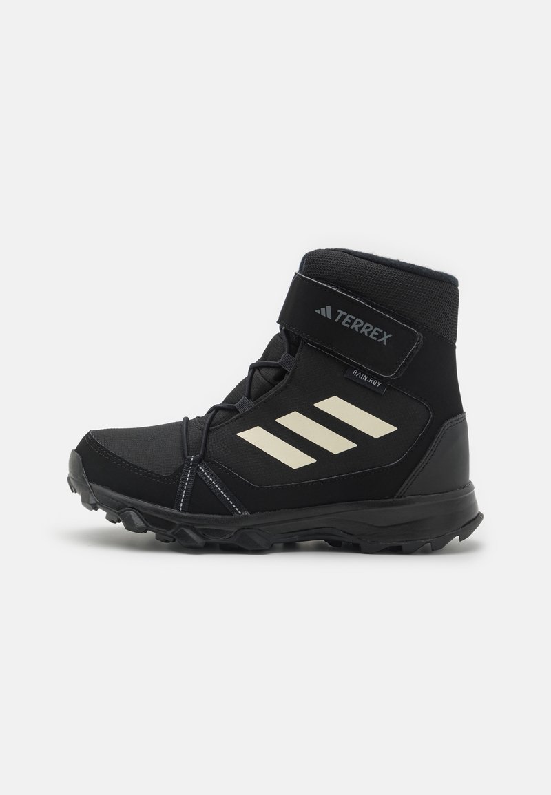 Botas de senderismo altas negras con parte superior de malla y sintético, suela de goma, correa de Velcro y tres rayas diagonales blancas en el costado.