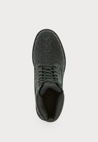 Black woven leather ankle boot with green accents, round toe, lace-up closure, padded collar, and textured surface detail.