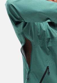 Veste bleu canard avec une ventilation zippée sur le côté, au tissu lisse et aux tirettes de fermeture éclair noires contrastantes pour un détail fonctionnel.