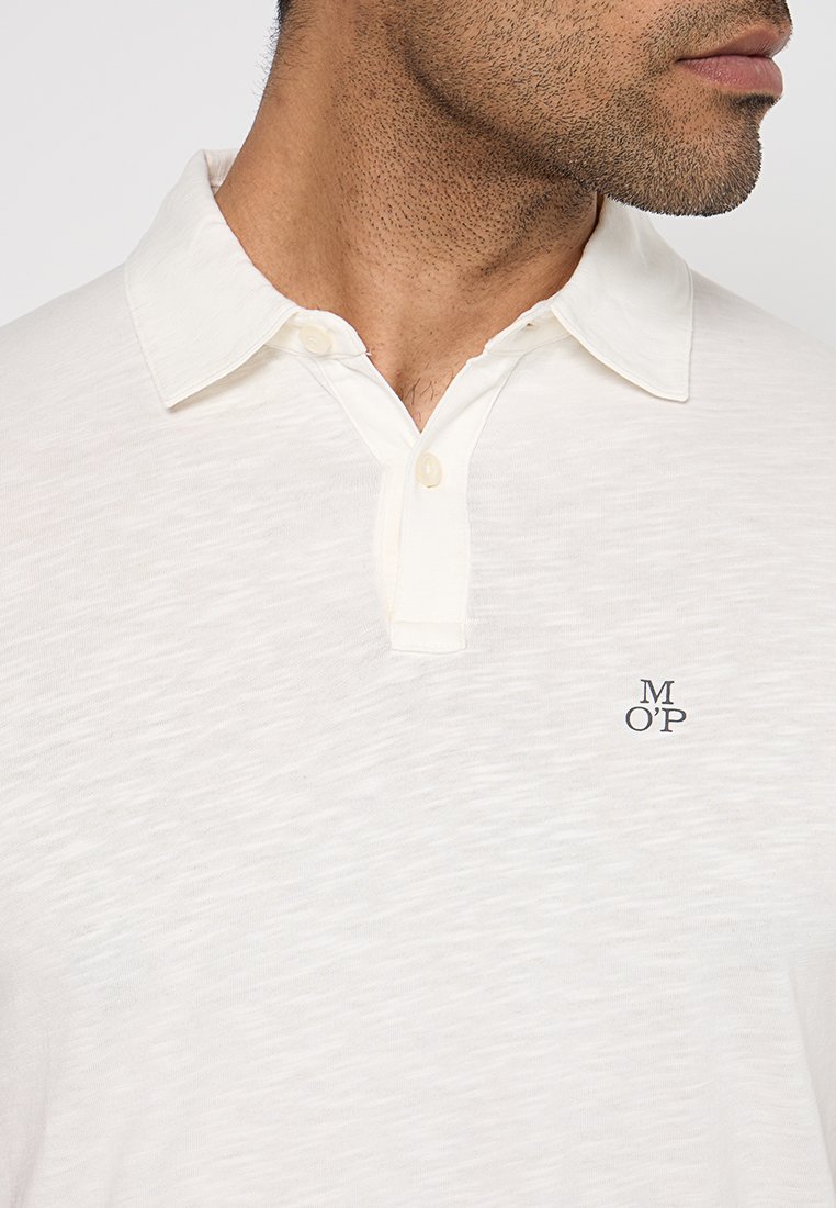 Weißes Polohemd mit kragenförmigem Ausschnitt, Knopfleiste und dezentem Muster. Es hat ein kleines dunkelblaues Logo auf der Brust.