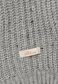 Šedá pletená tkanina s žebrovanou strukturou, se smetanově bílou etiketou se zlatým nápisem "Blkvis".