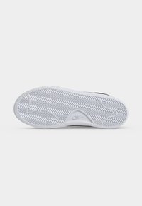 Λευκή καουτσούκ σόλα ενός παπουτσιού Nike με σχέδιο ψαροκόκκαλο και λογότυπο Nike ανάγλυφο κοντά στη φτέρνα, από κάτω.
