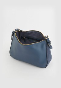 Niebieska skórzana torba z zamszu o zaokrąglonym kształcie, złoty zamek błyskawiczny, regulowany pasek oraz wyłożone wnętrze z kieszenią na zamek.