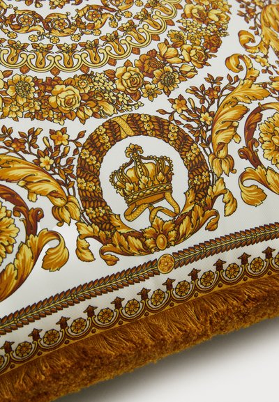 Διακοσμητικό μαξιλάρι με μοτίβο λουλουδιών και κορωνών σε χρυσό και μουσταρδί κίτρινο σε λευκό φόντο, με περίτεχνα τελειώματα.