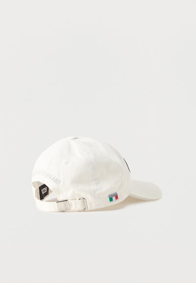 Λευκό καπέλο μπέιζμπολ με ρυθμιζόμενο λουράκι, μικρό ιταλικό σηματάκι και ασημένια αγκράφα σε απλό λευκό φόντο.