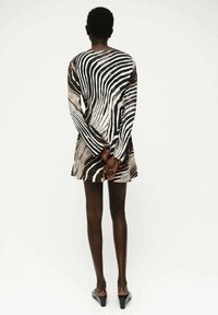 Langsleeve jurk met zebra-print in zwart en wit, aansluitende bodice, uitlopende rok, met een zachte textuur en minimalistisch ontwerp.