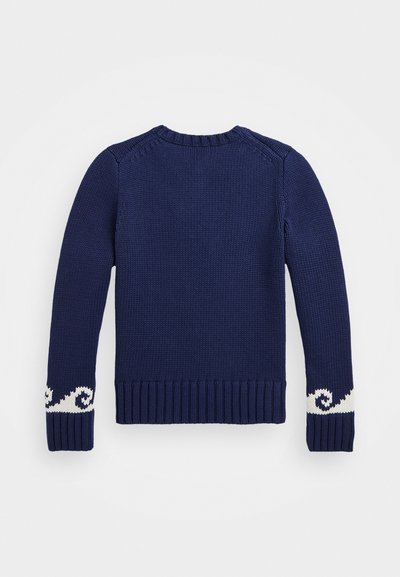 Tamsiai mėlynas megztinis su ilgomis rankovėmis, banguotais rankogaliais ir dekoratyvine balta bangų patternu netoli riešų. Klasikinio apvalaus kaklo dizainas.