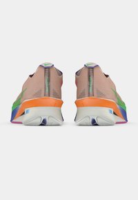 Sneakers Nike z przezroczystą, jasnobeżową cholewką, z neonowymi akcentami w kolorze zielonym, różowym i niebieskim oraz grubą, wielokolorową podeszwą.