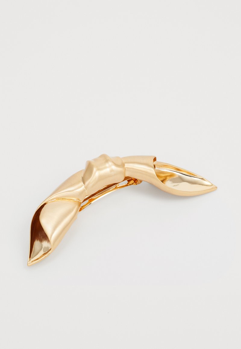 Guldtonad hårklämma med en vriden design, slät metallisk yta, spetsiga ändar och ett säkert spänne för fäste.