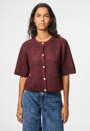 Bordeaux geribbelde cardigan met korte mouwen, voorzien van een ronde hals en crème knopen, gecombineerd met blauwe denim jeans.