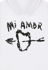 Felpa con cappuccio bianca con un disegno grafico nero che include il testo "Mi Amor", il contorno di un cuore e una freccia, il tutto realizzato in uno stile consumato.