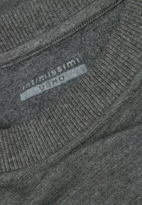 Dunkelgrauer Pullover mit ribbeliertem Rundhalsausschnitt, weichem Material und auffälligem Markenlabel, das in den Stoff genäht ist.